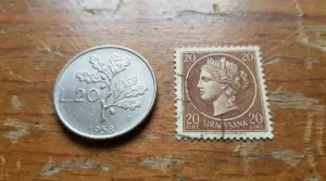 Moneta da 20 lire del 1958 e francobollo Siracusana da 20 lire su sfondo in legno