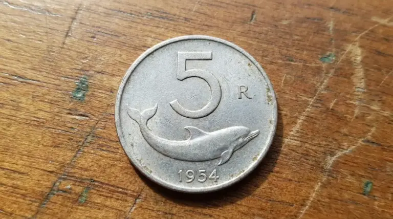 Moneta italiana da 5 lire del 1954 con delfino su sfondo in legno