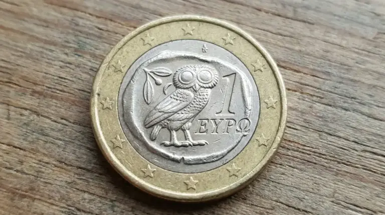 Moneta da 1 euro con disegno di un gufo su sfondo in legno