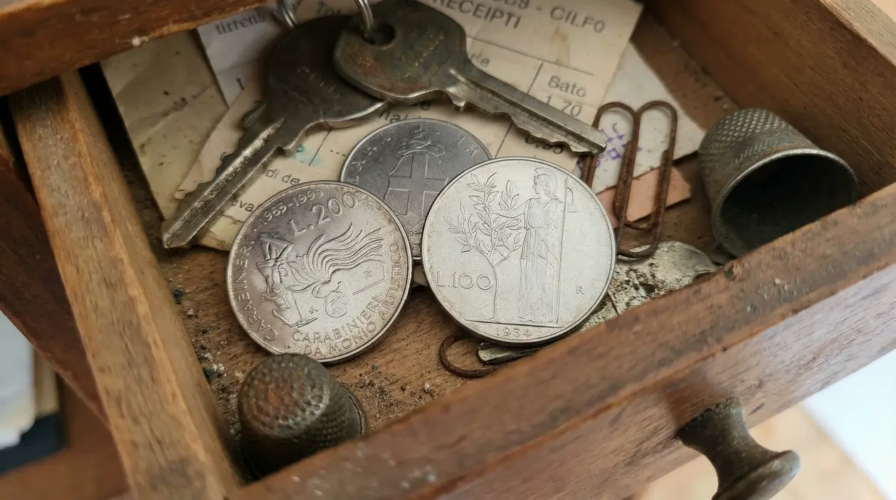 Vecchie monete italiane in un cassetto di legno con chiavi e oggetti di uso quotidiano