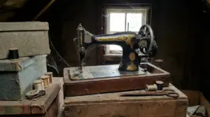 Vecchia macchina da cucire in un solaio polveroso con scatole e rocchetti di filo