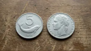 Vecchia moneta italiana da 5 lire con un delfino, accanto al lato con volto femminile