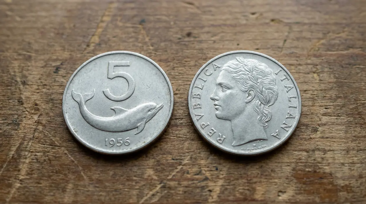Vecchia moneta italiana da 5 lire con un delfino, accanto al lato con volto femminile